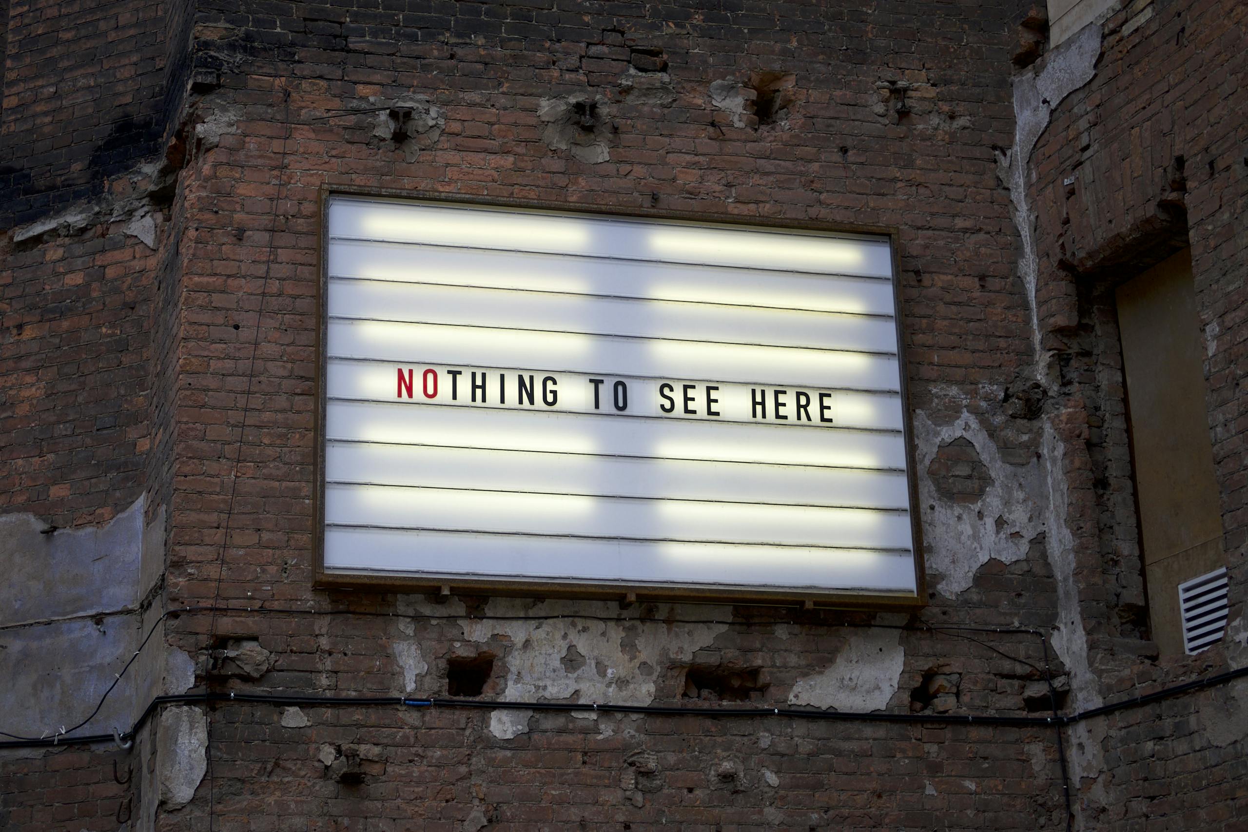 Une vieille enseigne lumineuse sur un mur de briques usé affiche l'inscription « Nothing to see here ».