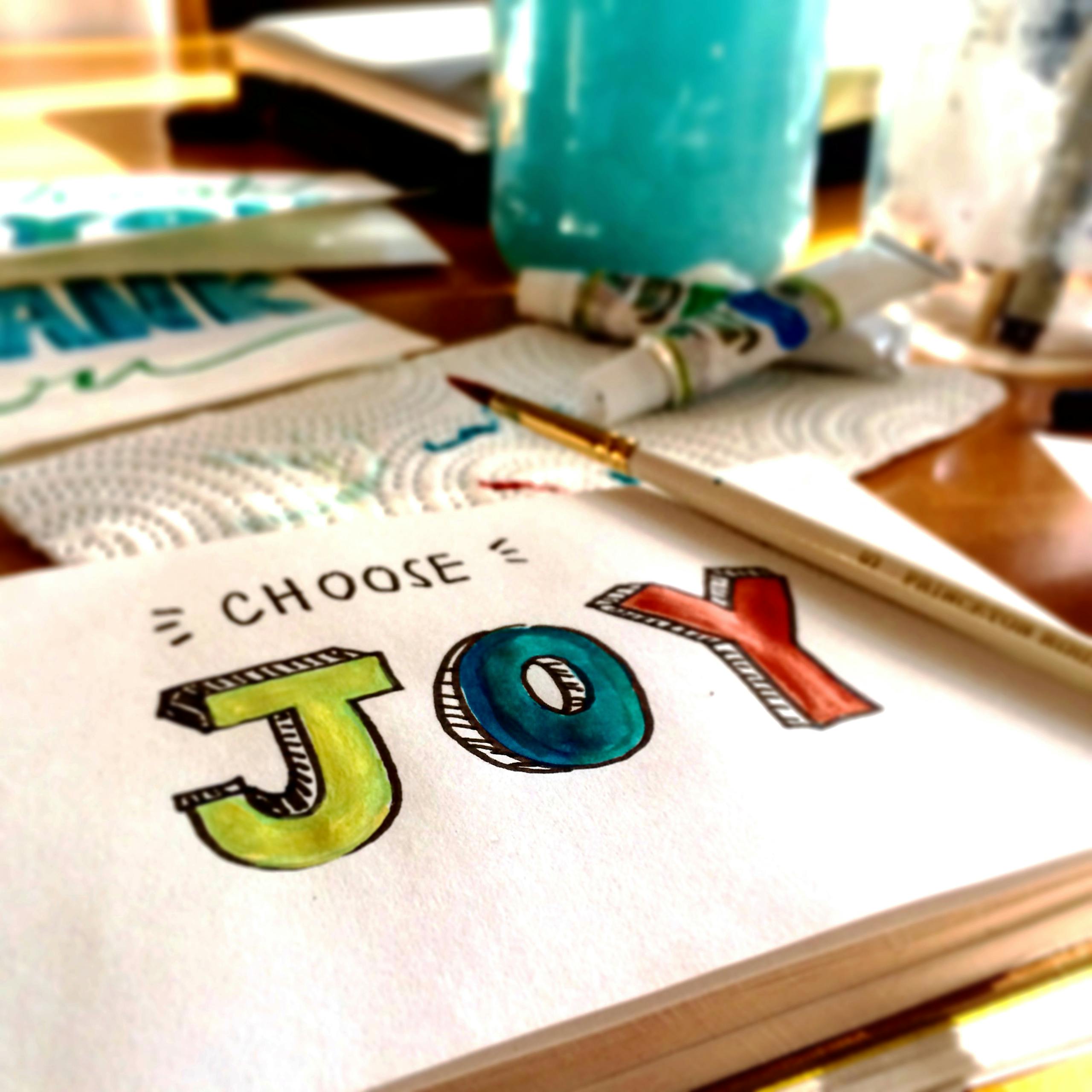 Une composition de peinture colorée avec l'inscription « Choose Joy », dans une ambiance créative.