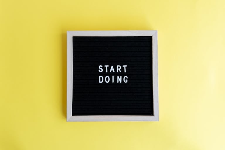 Black message board with 'Start Doing' on a bright yellow background for inspiration.